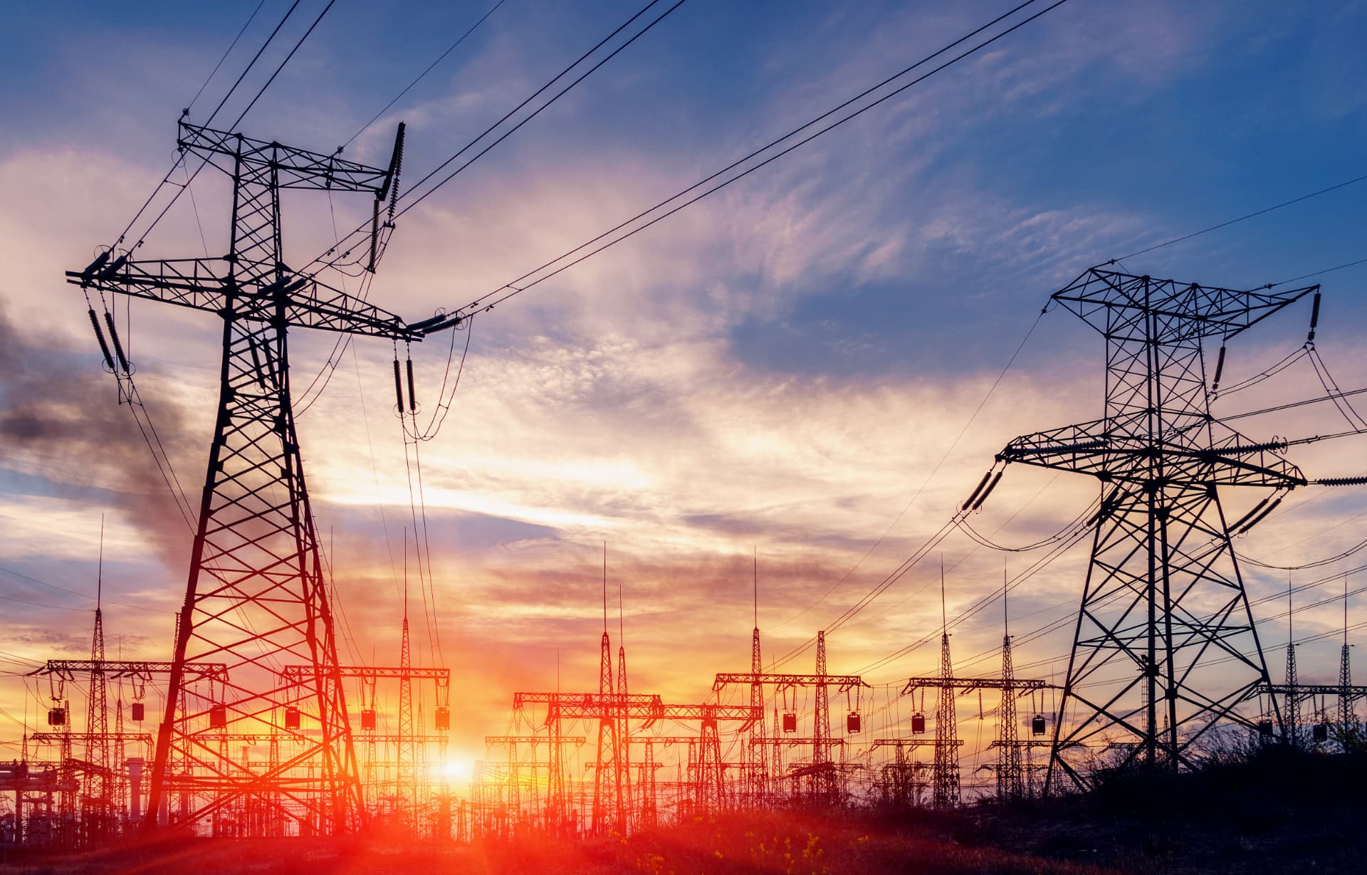 Power transmission towers against a sunset sky